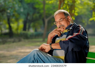 Indian man sitting at park and looking time in wristwatch. - Powered by Shutterstock