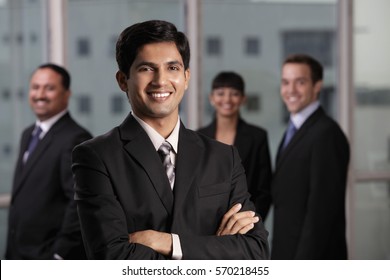 Indian man smiling in front of his colleagues