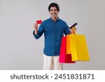 Indian man standing in front of camera with holding a credit card, tablet and shopping bags