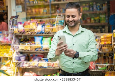 Indian man using smartphone at grocery shop. - Powered by Shutterstock