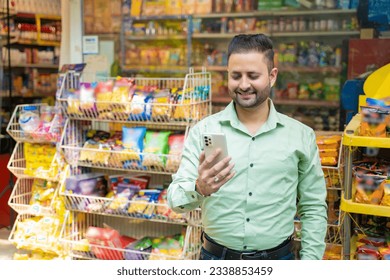 Indian man using smartphone at grocery shop. - Powered by Shutterstock