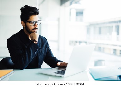 Indian Man Working On Laptop In Modern Office.