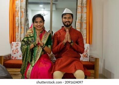 Indian Marathi Young Couple Smiling, Welcoming With Namaskara Pose Or Both Hands Folded While Wearing Traditional Festival Clothes In Their New Home. Home Loan, Health Insurance, House Warming Party.