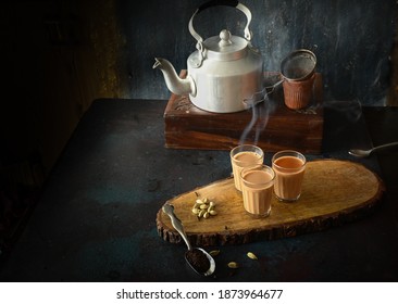 indian masala chai or tea ion ttraditional glasses, with kettle, spices and tea leaves on dark, wooden background. cafe, retro, restaurant, hotel concepts.