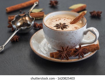 Indian Masala chai tea. Traditional Indian hot drink with milk and spices on dark stone background close up.
