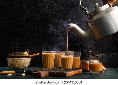 indian masala chai or tea in traditional glasses, with kettle, spices and tea leaves on dark, wooden background. cafe, retro, restaurant, vintage, ethnic, healthy, hotel concepts.