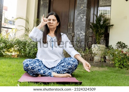 Indian Mature woman doing yoga at home garden