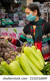 Indian Mature Woman Wearing Protective Face Mask And Buying Vegetables From Outdoor Market During The Third Wave Of Coronavirus, COVID-19 Pandemic Outbreak In Indian.    