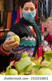 Indian Mature Woman Wearing Protective Face Mask And Buying Guava From Outdoor Market During The Third Wave Of Coronavirus, COVID-19 Pandemic Outbreak In Indian.    