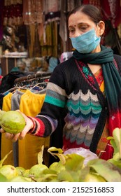 Indian Mature Woman Wearing Protective Face Mask And Buying Guava From Outdoor Market During The Third Wave Of Coronavirus, COVID-19 Pandemic Outbreak In Indian.    