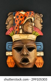 Indian Mayan Aztec wooden carved painted mask with roaring jaguar and human faces isolated on black paper background