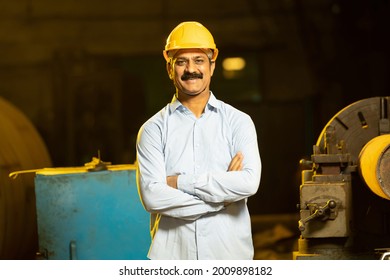 Indian Mechanical Engineer wearing safety yellow hard hat smiling while standing cross arm. Industrial factory worker concept.  - Powered by Shutterstock