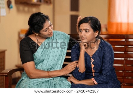 Indian middle aged mother consoling worried daughter at home - concept of parental care, family support and concern or compassion