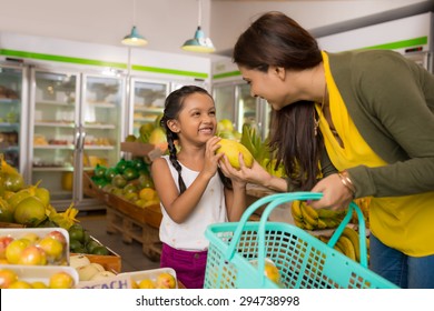 Indian Mother And Daughter Choosing Fruits At The Grocery Store