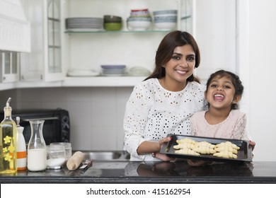 Indian Mother And Daughter Showing Tray With Croissants