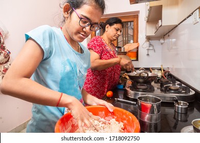 Indian Mother And Daughter Working In Kitchen Together, Young Girl Kneading Flour. 