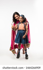 Indian Mother Helping School Girl With Uniform Getting Ready With Lunch Box, Hair Style Or Waiting For School Bus