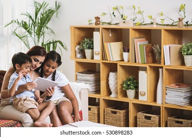 Indian Mother And Her Children Watching Something On Tablet Computer