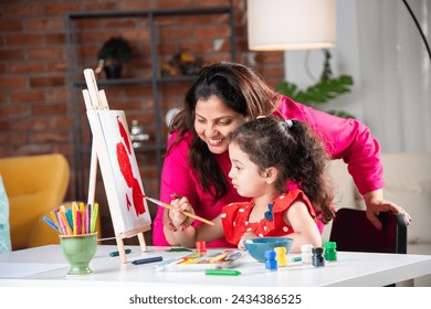 Indian mother and little daughter painting on easel together at home - Powered by Shutterstock