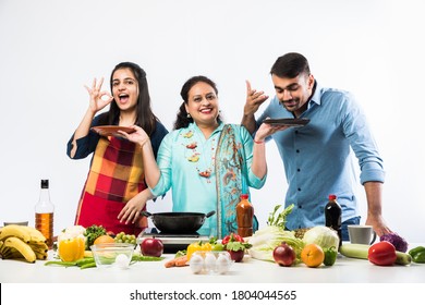 Indian Mother or Sister making food for young kids in kitchen