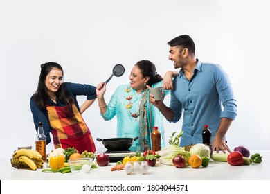 Indian Mother Or Sister Making Food For Young Kids In Kitchen