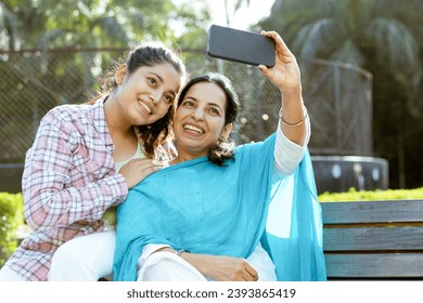 Indian mother and young daughter taking selfie together in outdoor garden, Motherhood , Mother and Daughter relation ship concept - Powered by Shutterstock