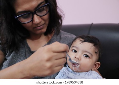 An Indian Mothher Feeding Milk To A Baby Boy With A Spoon