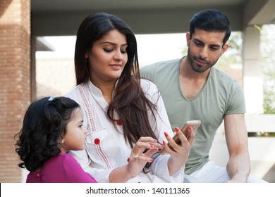 Indian Or Multi Ethnic Family , Mother Showing Something To Her Daughter On Phone Tablet