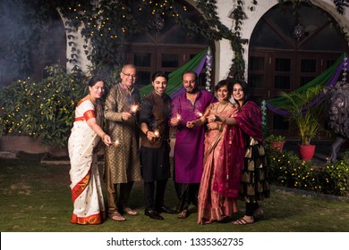 Indian Multigenerational Family Celebrating Diwali Festival By Playing With Firecrackers Outside Home