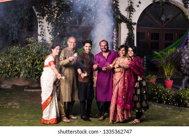 Indian Multigenerational Family Celebrating Diwali Festival By Playing With Firecrackers Outside Home