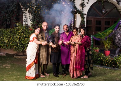 Indian Multigenerational Family Celebrating Diwali Festival By Playing With Firecrackers Outside Home