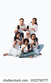 Indian Multigenerational Family Showing Empty Smartphone Screen, Sitting Against White Background