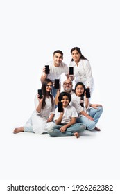 Indian Multigenerational Family Showing Empty Smartphone Screen, Sitting Against White Background