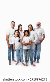 Indian Multigenerational Family In White Cloths Standing And Looking At Camera Against White Background