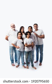 Indian Multigenerational Family In White Cloths Standing And Looking At Camera Against White Background