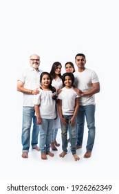 Indian Multigenerational Family In White Cloths Standing And Looking At Camera Against White Background