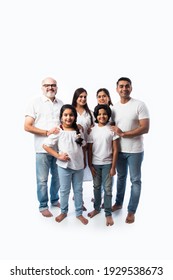 Indian Multigenerational Family In White Cloths Standing And Looking At Camera Against White Background