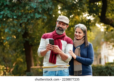 Indian old couple using smartphone at park - Powered by Shutterstock