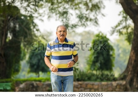 Indian old man running or jogging at park