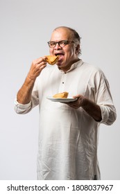 Indian Old Man Or Senior Man Eating Samosa Or Veg Pastry