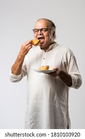 Indian Old Man Or Senior Man Eating Samosa Or Veg Pastry