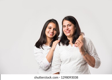 Indian old mother with young Daughter standing isolated over white background, while wearing white top and blue jeans. selective focus