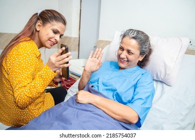 Indian Old Senior Patient In Hospital Bed Using Smart Phone Doing Video Call To Descendant Relatives With Young Daughter Sitting By Side - Elderly Medical And Healthcare Concept