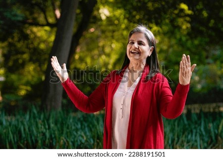 Indian old woman doing laughing yoga at park