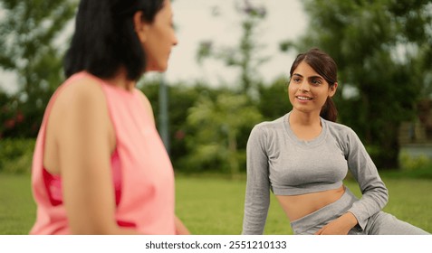 Indian older relax confident healthy woman with beautiful cute teenager girl sitting on mat talk gossip about warm up workout exercise during break time enjoy spend time together outdoor home garden - Powered by Shutterstock