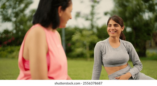 Indian older relax confident healthy woman with beautiful cute teenager girl sitting on mat talk gossip about warm up workout exercise during break time enjoy spend time together outdoor home garden - Powered by Shutterstock