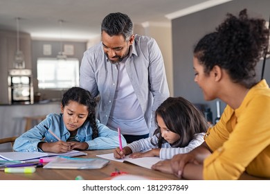 Indian parents helping children with their homework at home. Middle eastern father and african mother helping daughters studying at home. Little girls completing their exercises with the help of dad. - Powered by Shutterstock