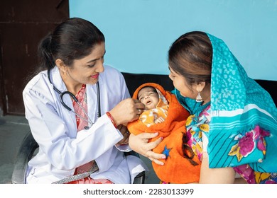 Indian pediatrician doctor examine new born baby at village, Mother wearing sari get infant check by medical person. Rural healthcare camp concept. - Powered by Shutterstock