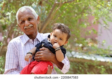 Indian A Picture Of Grandfather And Adorable Baby Outside . Asian Old Man Holding His Grandson In His Arms . Pali Rajasthan , India