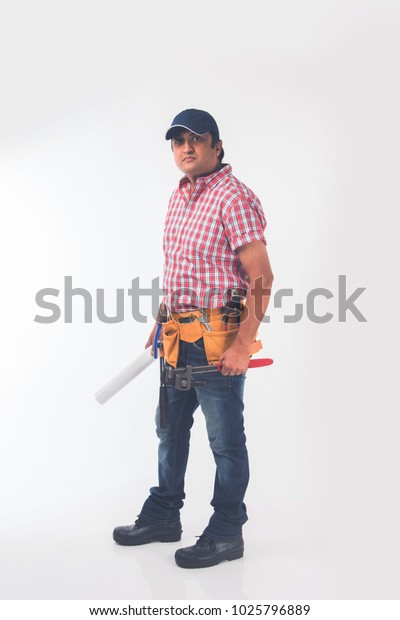 Indian plumber\
holding drawing roll and Pipe wrench or plumbing spanner, standing\
isolated over white\
background\
